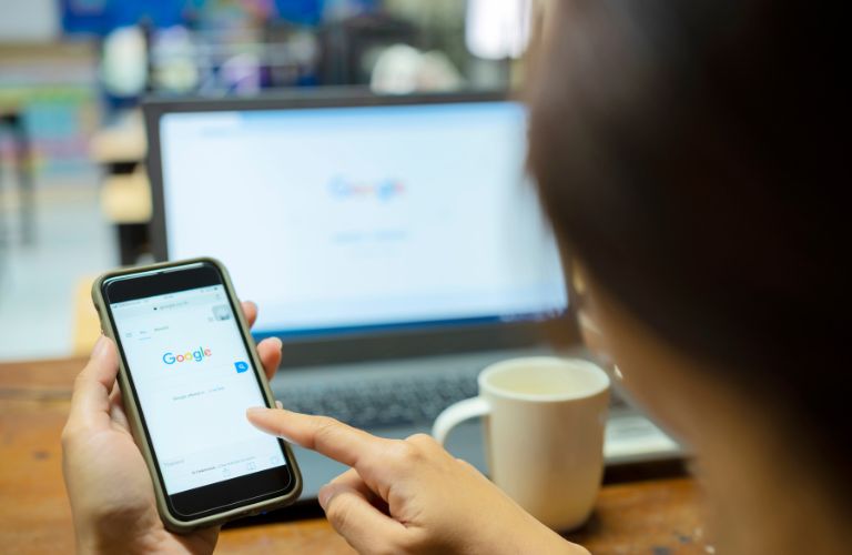 Person Using Google on Phone and Laptop