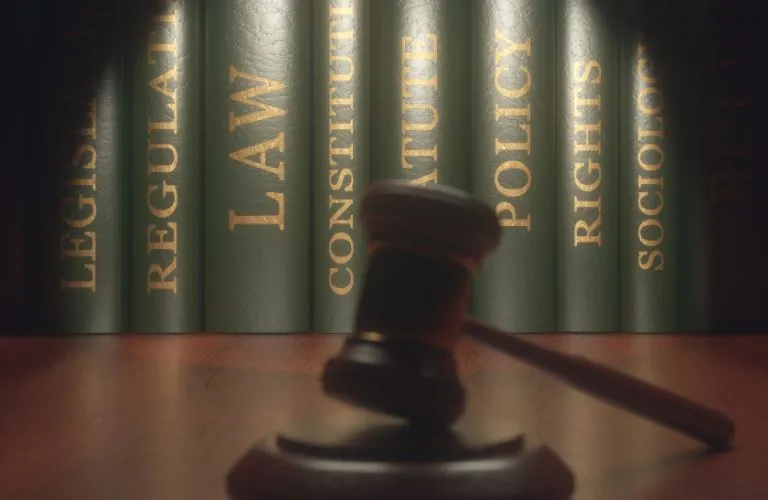 Gavel in Foreground of Desk with Light on Legal Books
