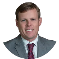 Portrait of a smiling man wearing a gray suit and red patterned tie.