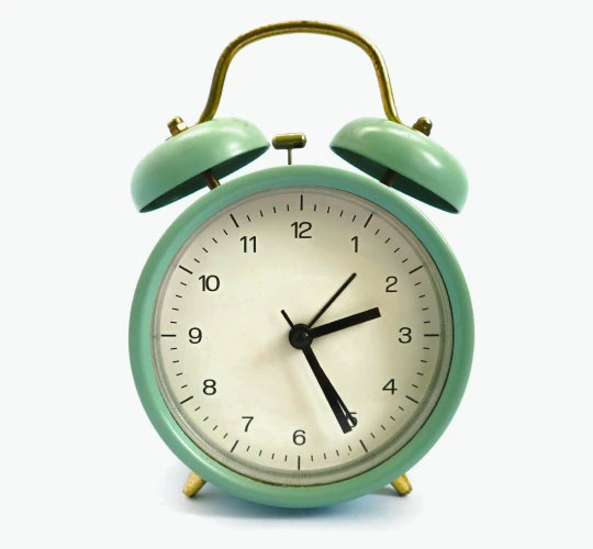A vintage teal alarm clock on a dark background.
