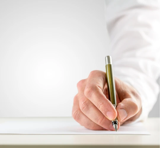 Close-up of a hand signing a document with a pen.