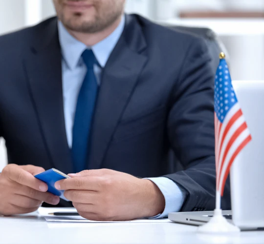 Attorney David Cox seated at a desk in a suit beside an American flag.