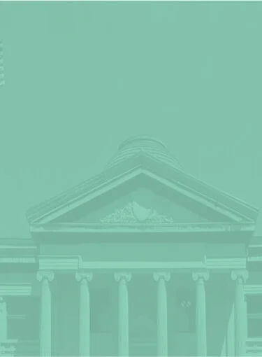 Classical building facade with columns and triangular pediment against clear sky.