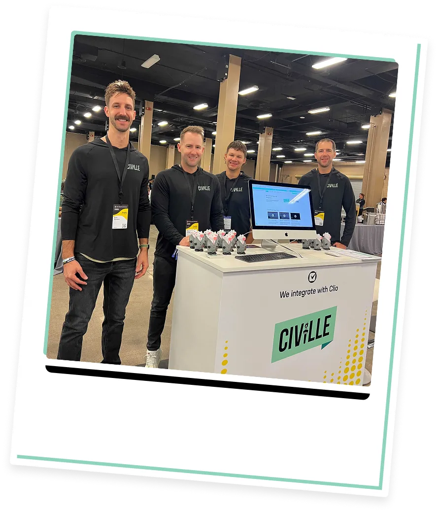 Four men in black Civille-branded shirts standing behind a white exhibition booth with a computer and promotional items.