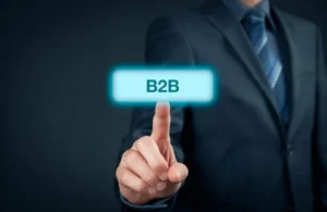Businessman in dark suit touching illuminated blue button labeled "B2B" on dark background.